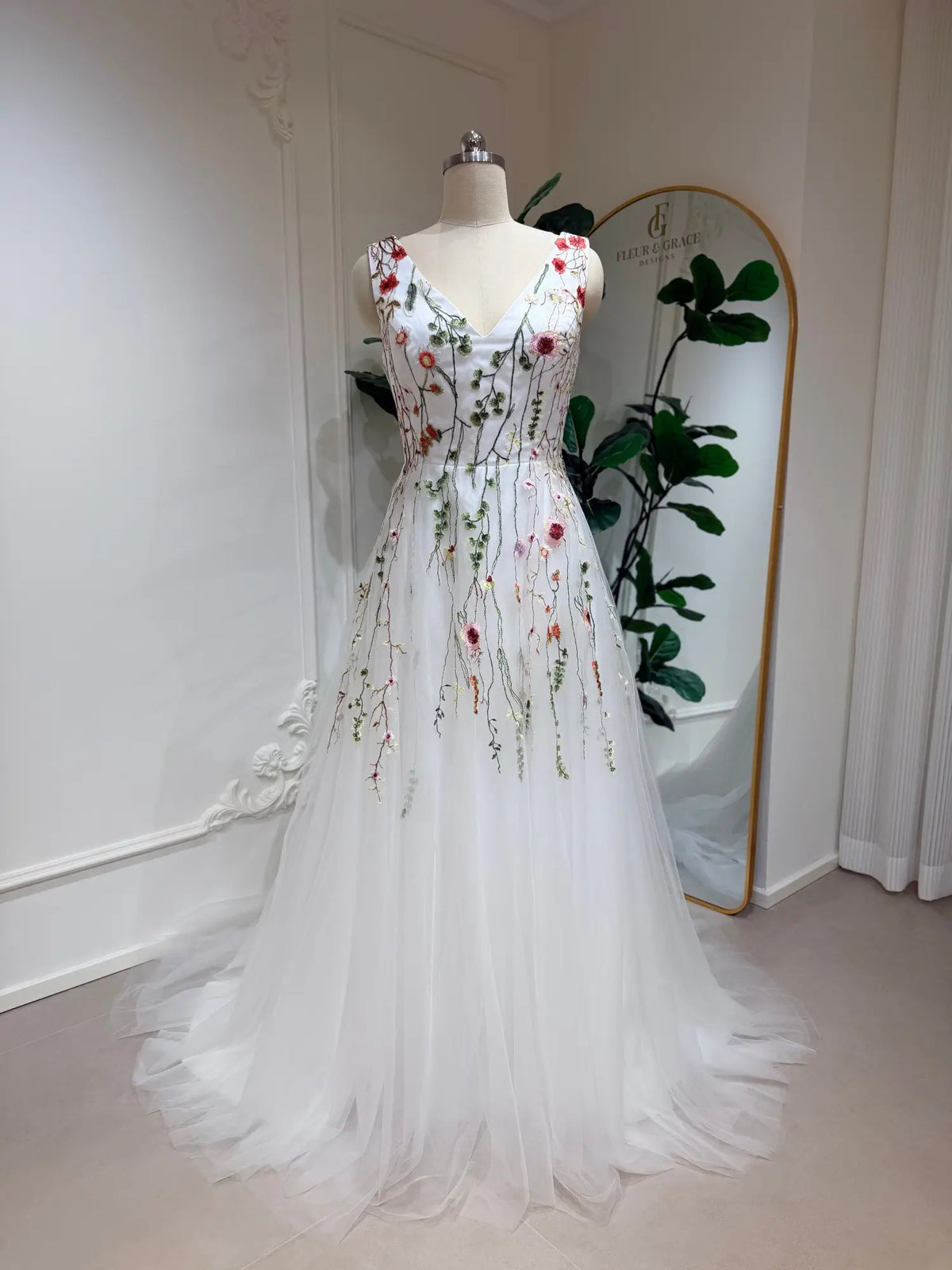 A-line wedding dress with V-neck, featuring colorful botanical embroidery on a flowing white tulle skirt.