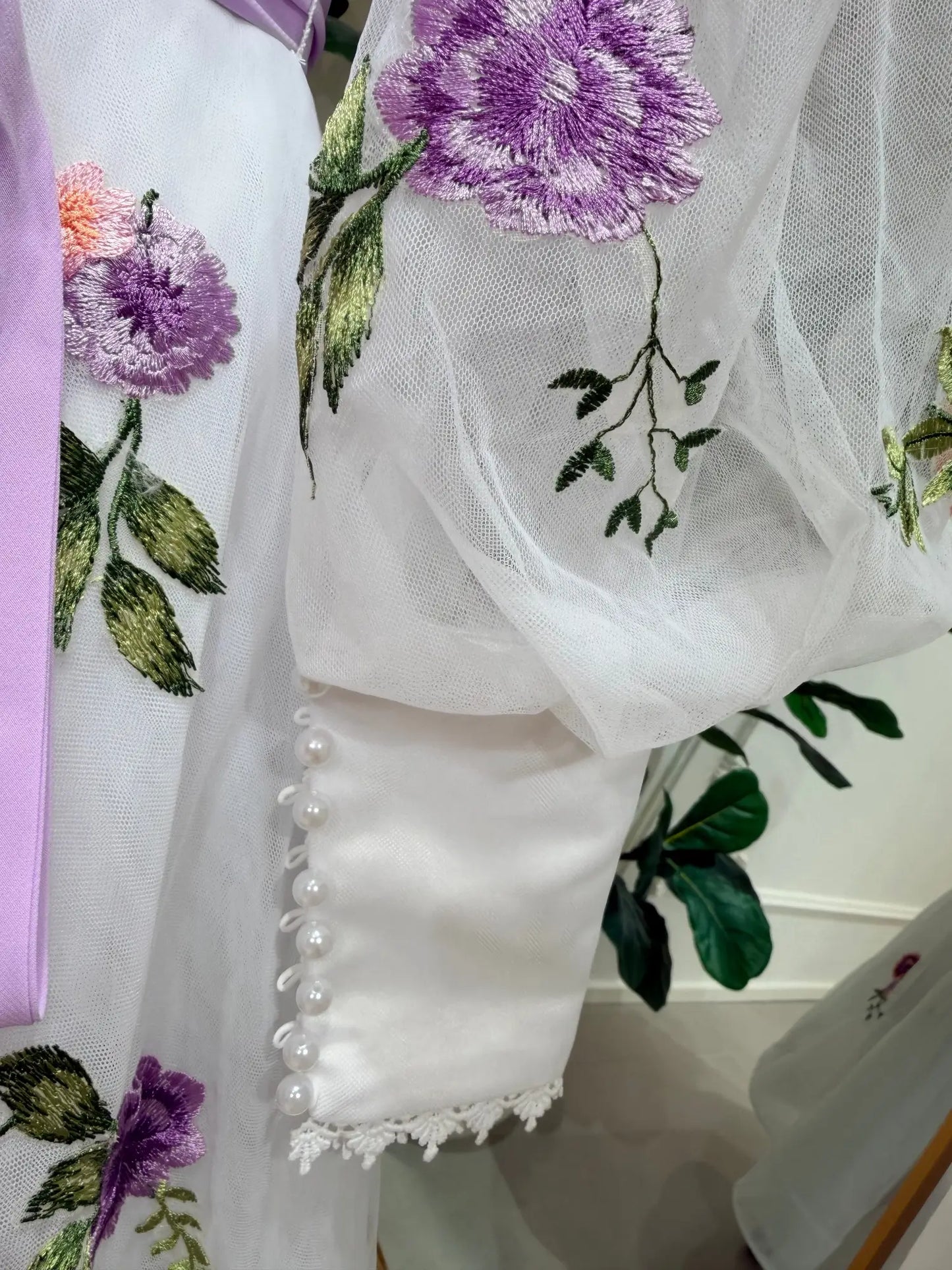 White tulle bridal gown with lavender floral embroidery, puff sleeves, and pearl-button cuffs.