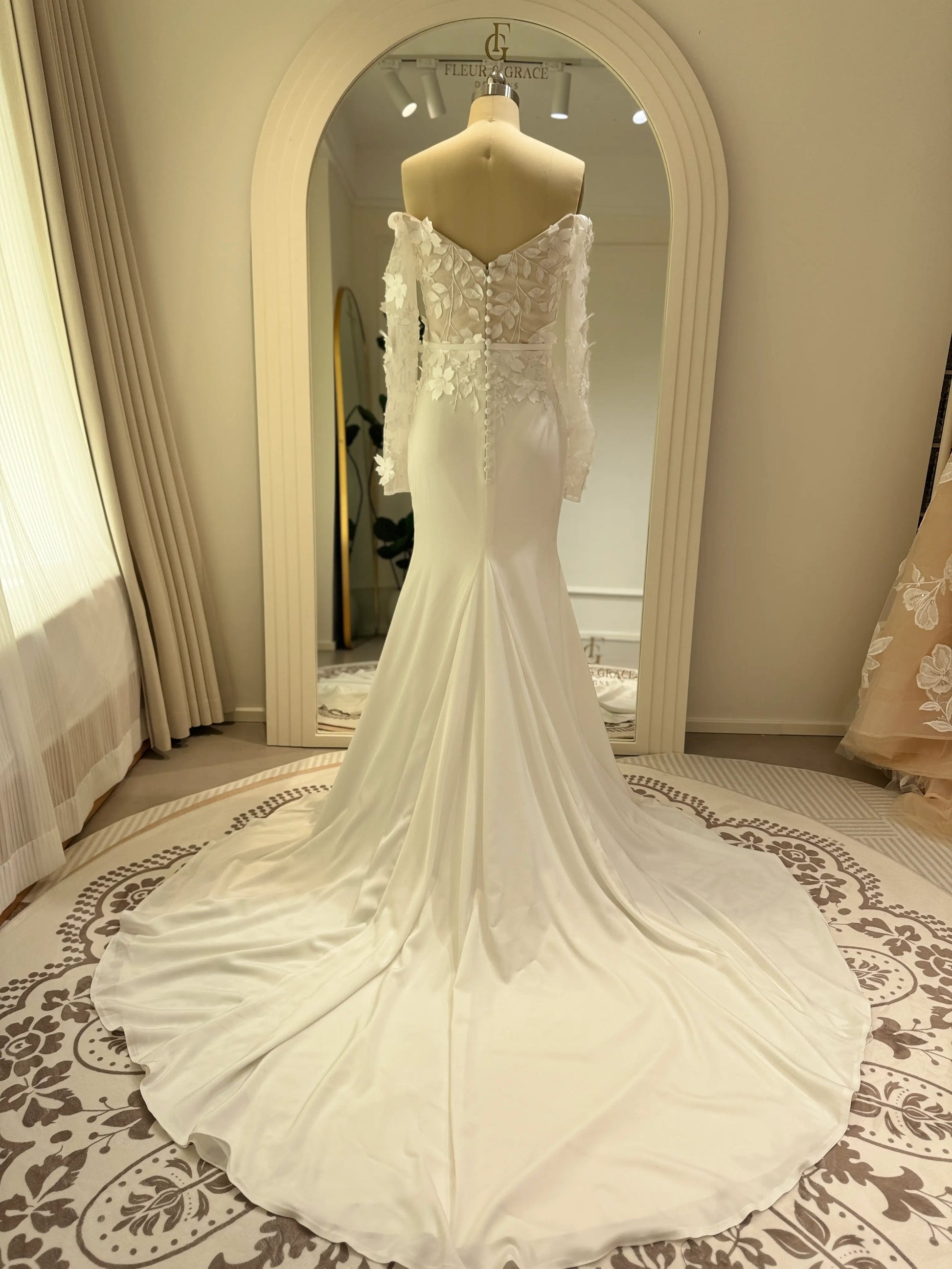 Zoe Gown by Fleur&Grace – minimalist matte crepe wedding dress with 3D floral lace bodice, long off-the-shoulder sleeves, side slit, and train, perfect for modern and romantic weddings.