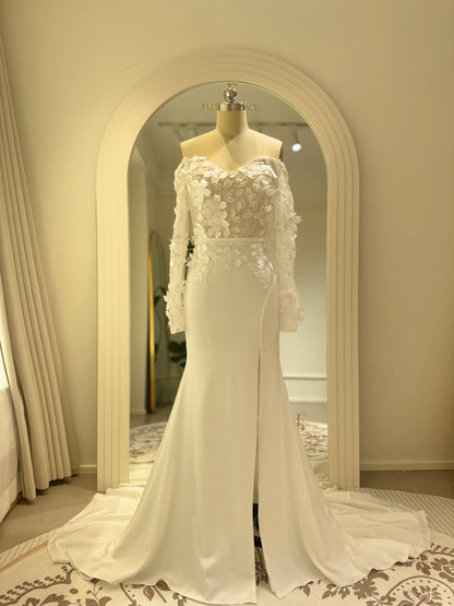 Minimalist white crepe mermaid wedding dress with 3D floral bodice, off-the-shoulder long sleeves, and a side slit.