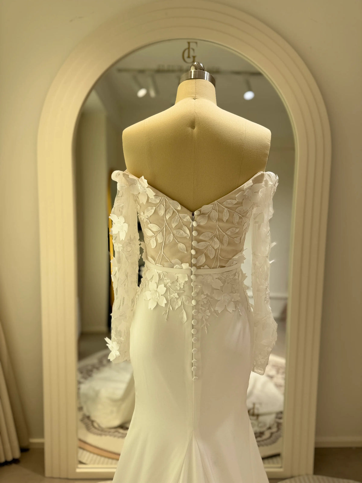 Zoe minimalist crepe wedding gown with 3D floral bodice, off-the-shoulder long sleeves, and button-back detail.