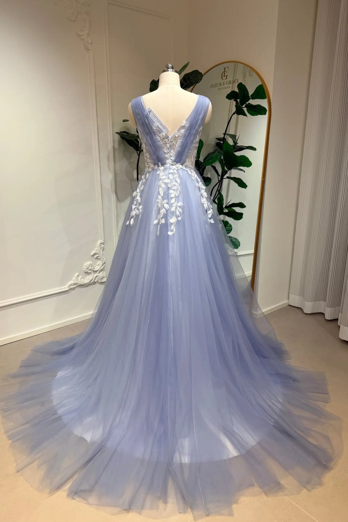 Dusty blue A-line wedding gown with tulle skirt, V-neck back, and intricate white floral lace appliqué.