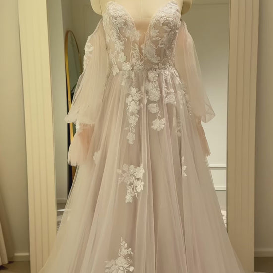Aure Gown by Fleur&Grace Designs – romantic floral embroidered wedding dress with plunging neckline, removable long sleeves, soft tulle skirt, and A-line silhouette, perfect for whimsical weddings and elopements.