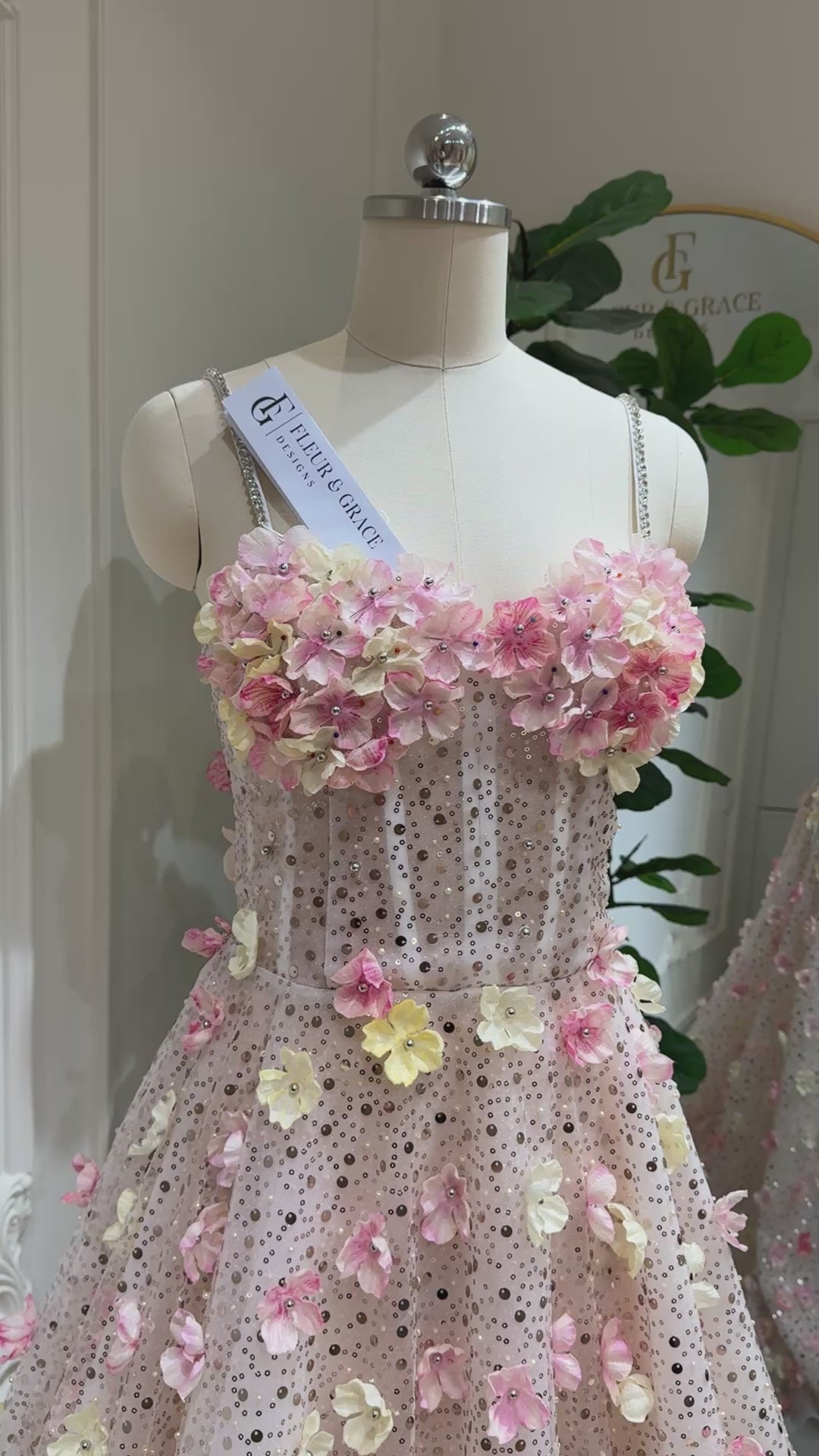 The Alice Gown FG018 is a dreamy, fairytale-inspired dress perfect for prom, photoshoots, and formal events. Crafted with exquisite beaded lace and adorned with delicate handmade 3D flowers in soft pink and yellow tones, this gown shimmers with every step. Featuring a romantic sweetheart neckline, lace‑up back for an adjustable fit, and thin stone‑accented straps, the Alice Gown blends fantasy with elegance. The regal court train adds a show‑stopping finish, making it ideal for prom nights, garden par